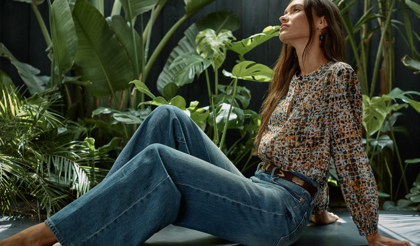 Model sitting wearing printed shirt and jeans 