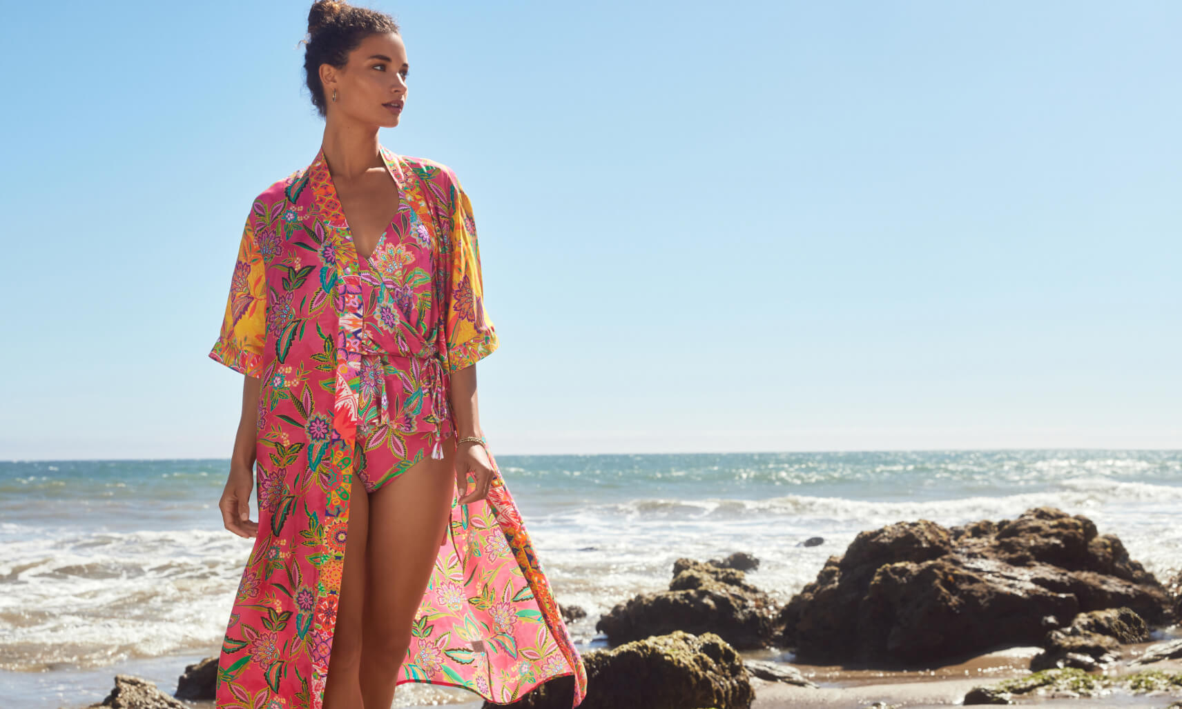 Model on a beach in a printed one-piece and cover-up kimono