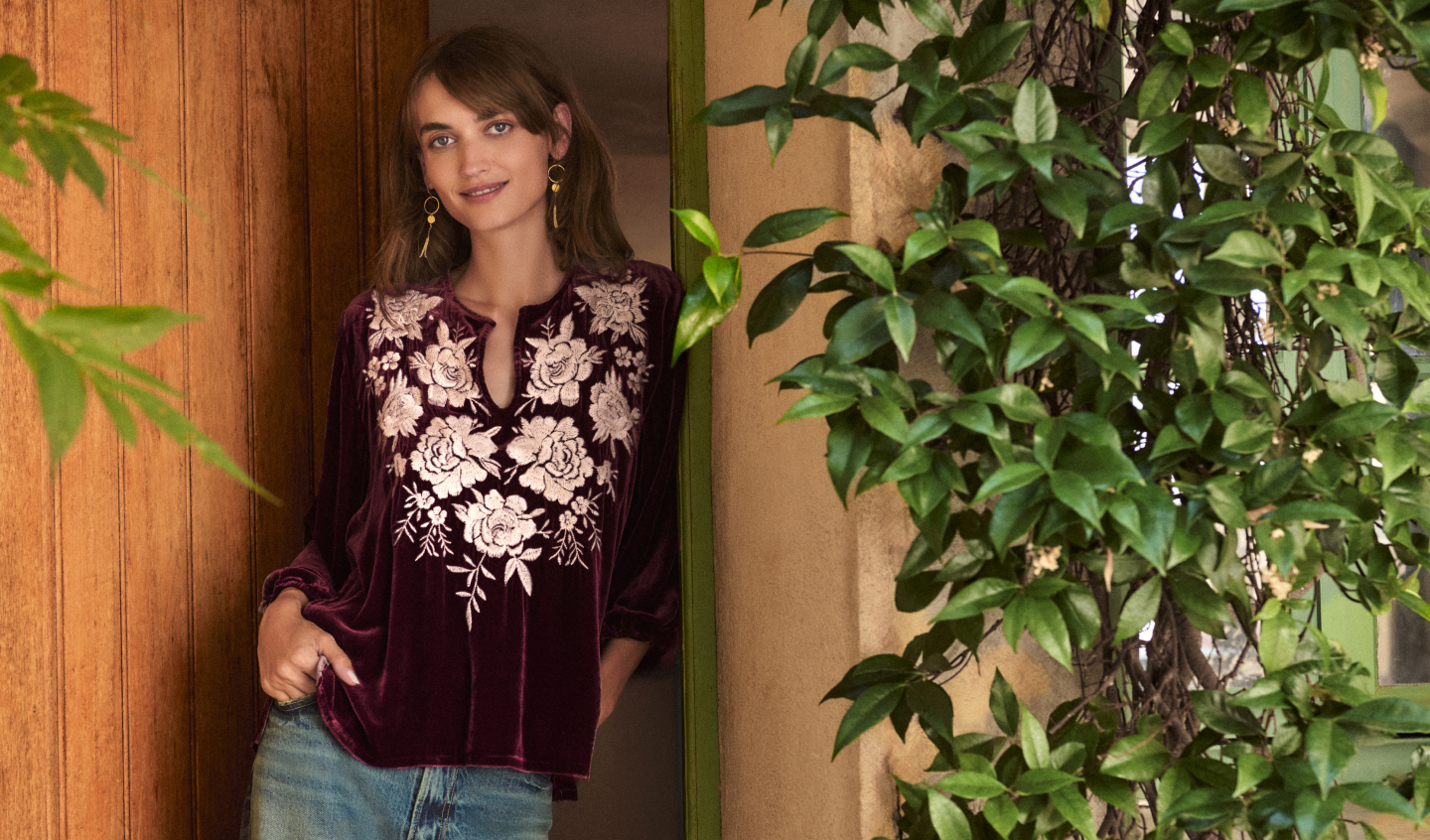 Model standing wearing embroidered velvet top