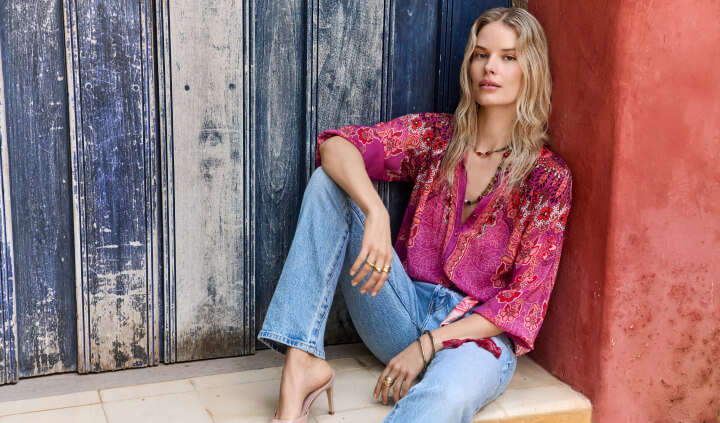 Model sitting wearing silk blouse with jeans